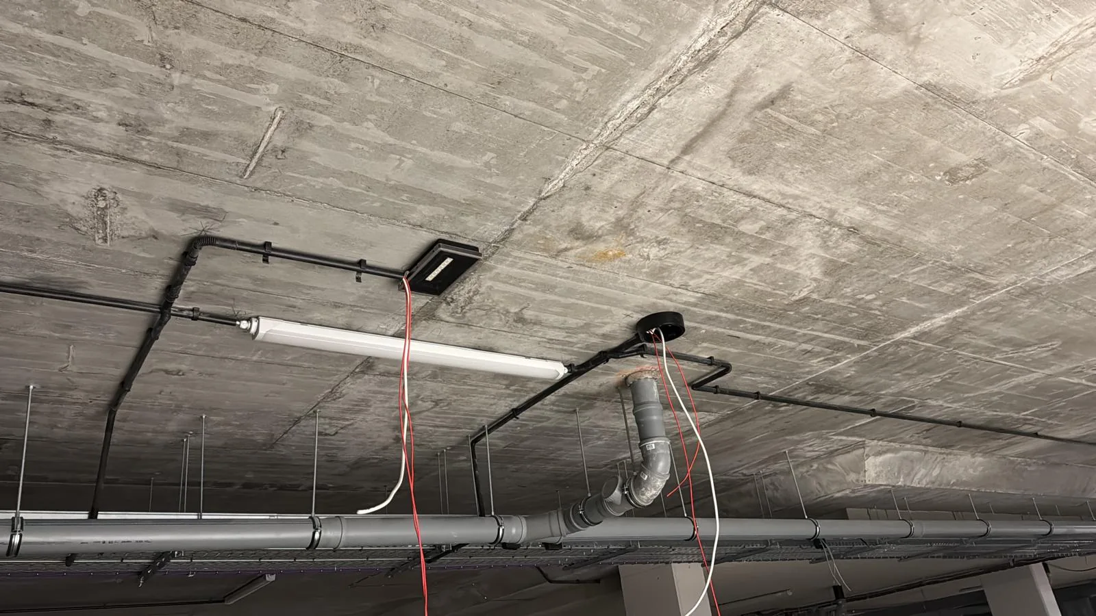 Trasy instalacyjne i oświetlenie na betonowym stropie